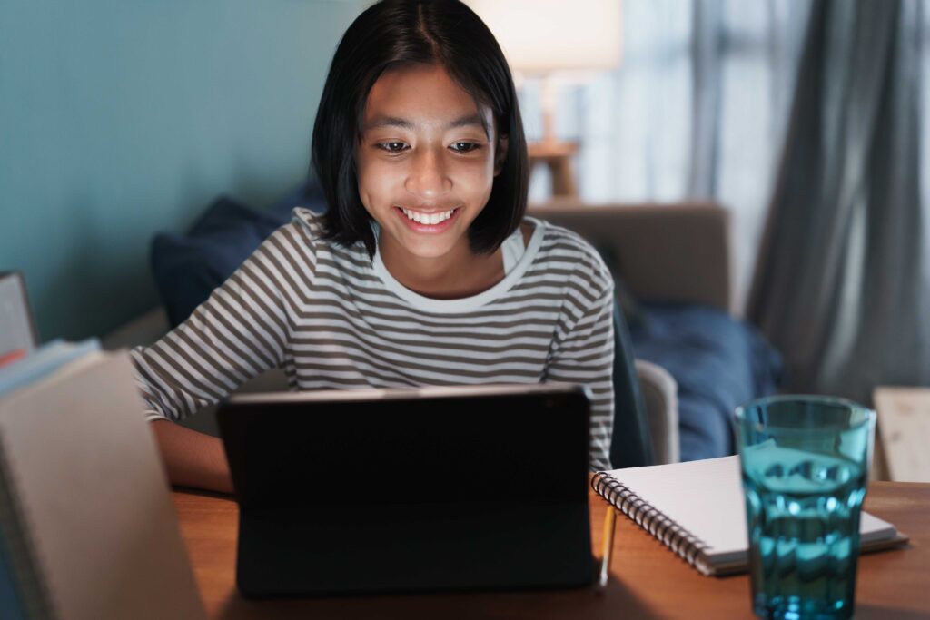 Happy Asian girl is studying online with tablet at desk at night, Asia child smile and expression emotion cheerful on the face her. Concept of online learning at home